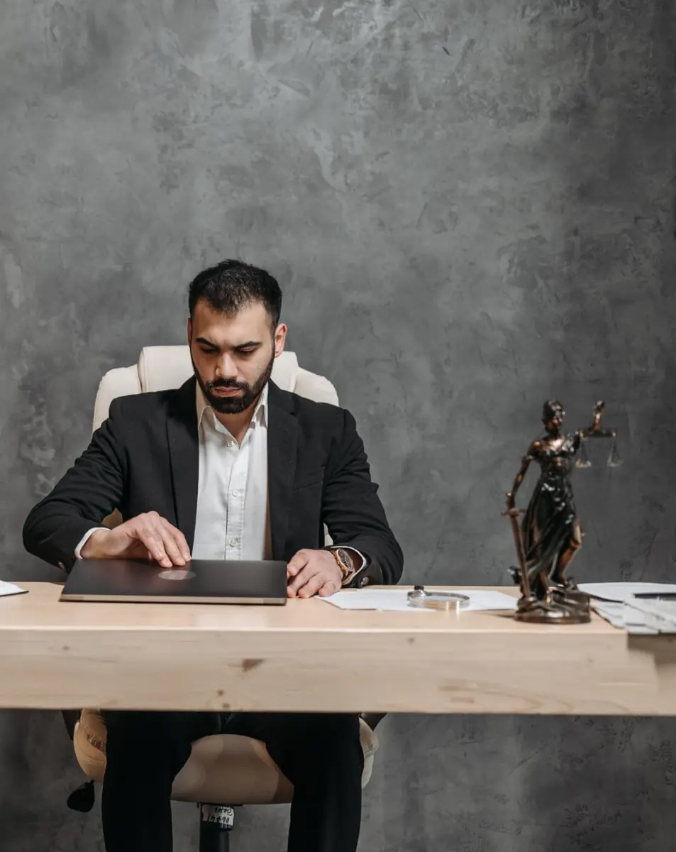 Attorney at his desk beside a Lady Justice statue